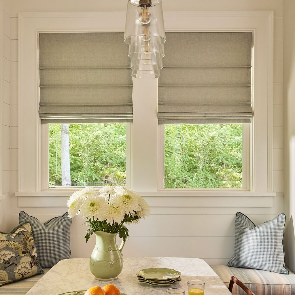 Front Fold Roman Shades in a near neutral green over windows in a kitchen nook.