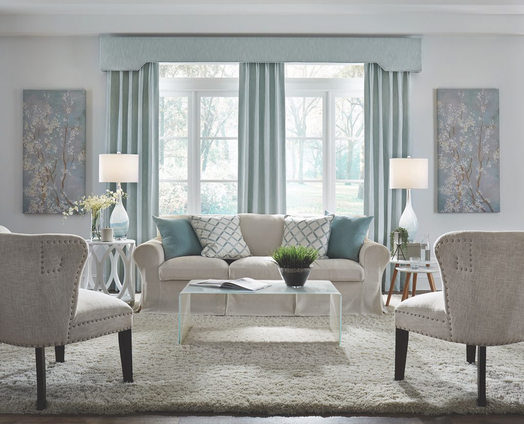 A living room that feels large and open in whites, light neutrals and pale blues.