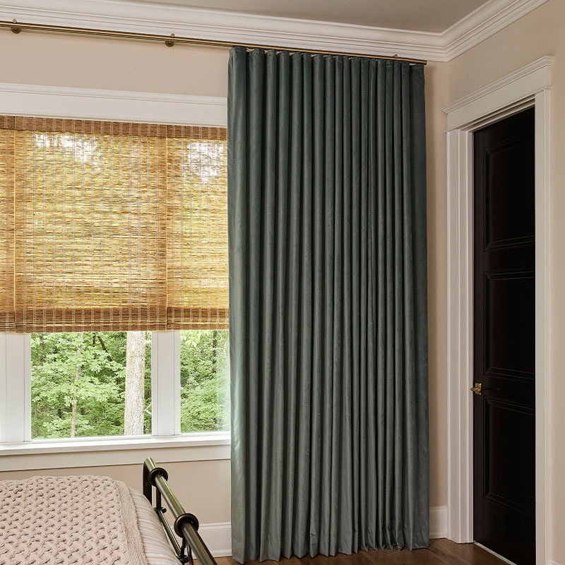 A bedroom with dark green velvet drapery on Forest Drapery Hardware.