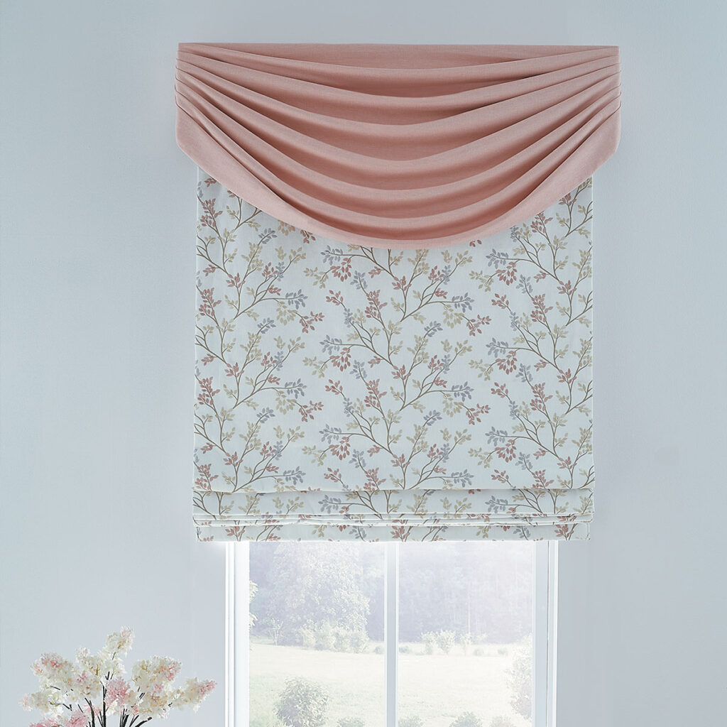 A pink Westlake Swag over a Flat Roman Shade with a delicately embroidered pastel floral on a white background in a room with white walls and a bouquet of pink and white flowers.