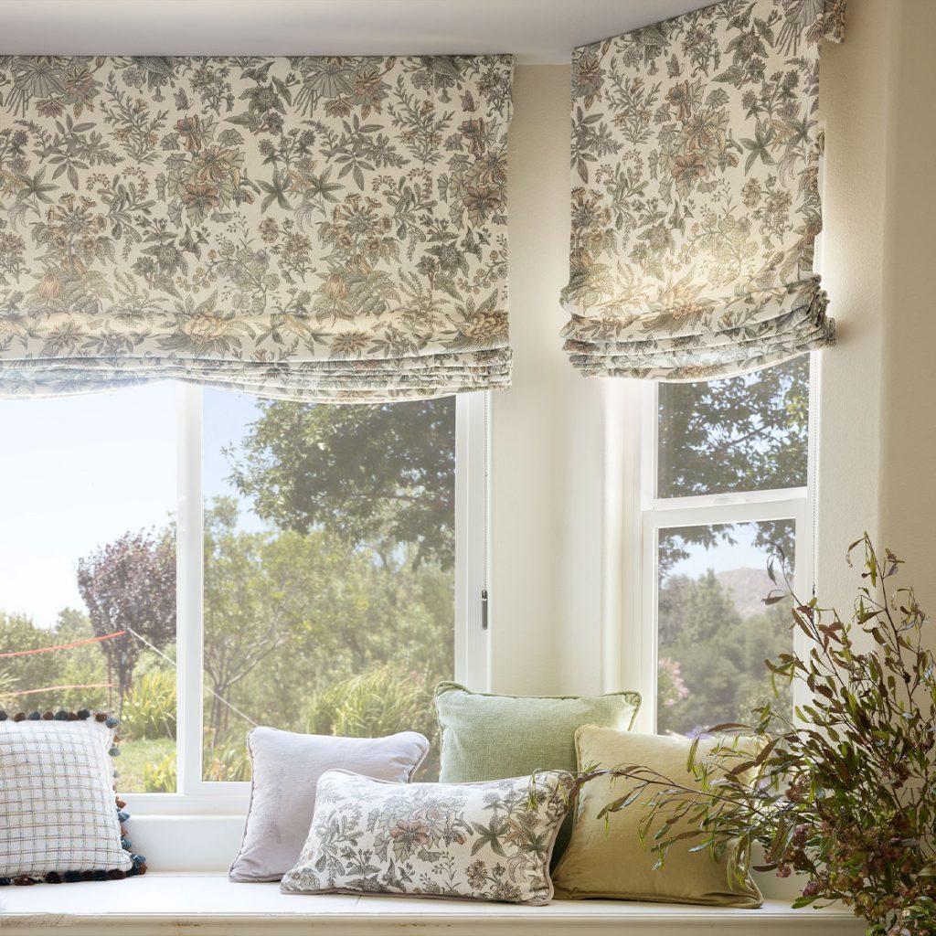 Soft Roman Shades with a large scale floral print in a sitting area's bay window.