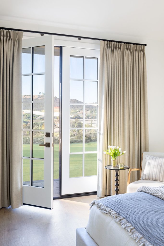 Two Finger Pinch Pleat Drapery over French doors in a sunny bedroom.
