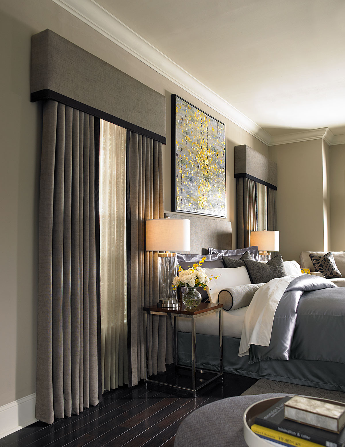 A dark neutral bedroom with draperies, sheers and cornices on the windows.